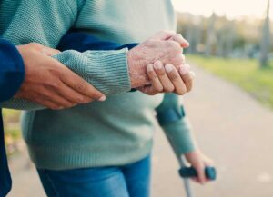 Elderly residents talking with a nurse in a bright, homelike common area with comfortable seating.